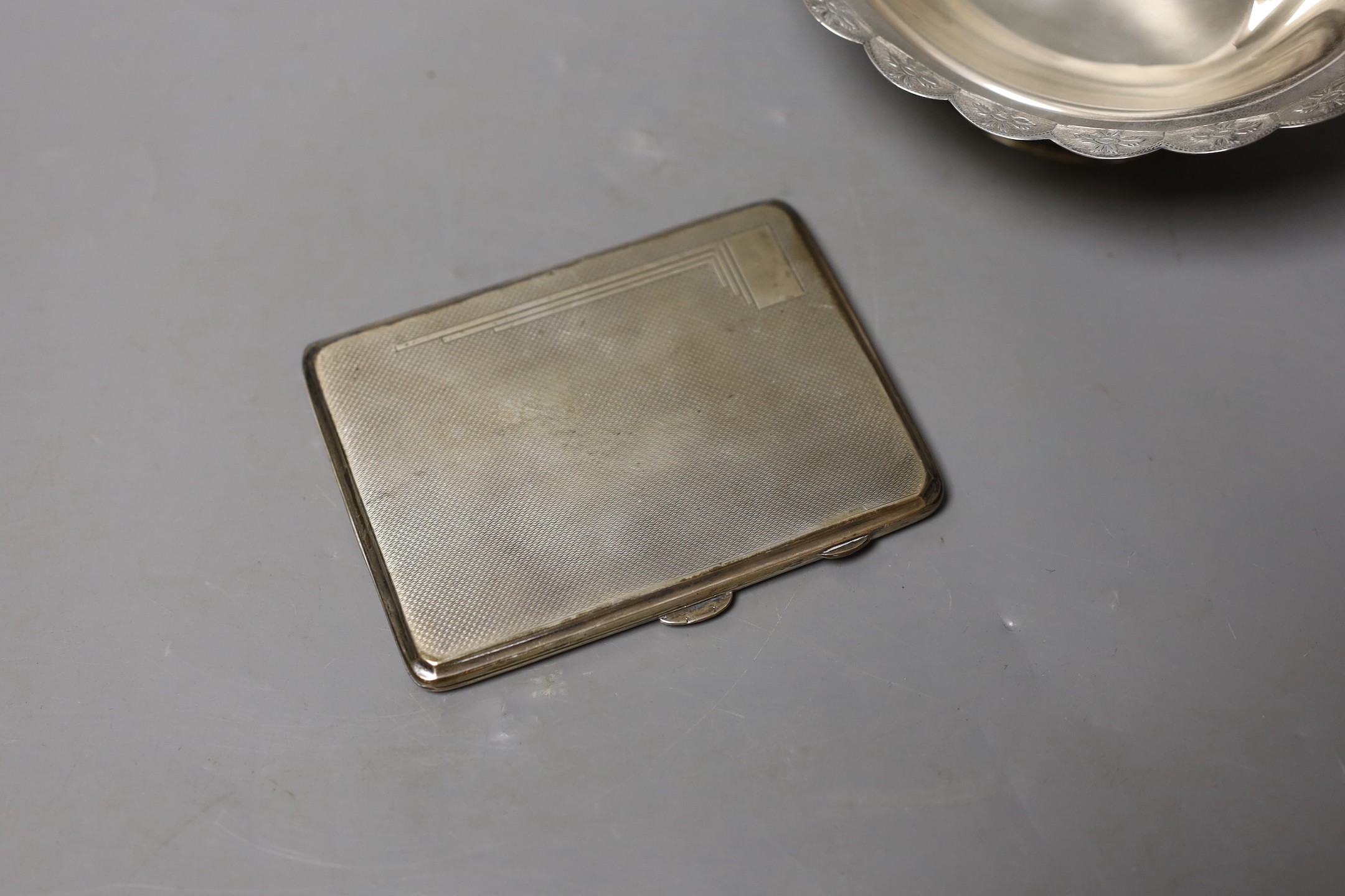 An Elizabeth II silver oval dish, with cusped border, by Mappin & Webb, Birmingham, 1985, length 16cm and an earlier engine turned silver cigarette case